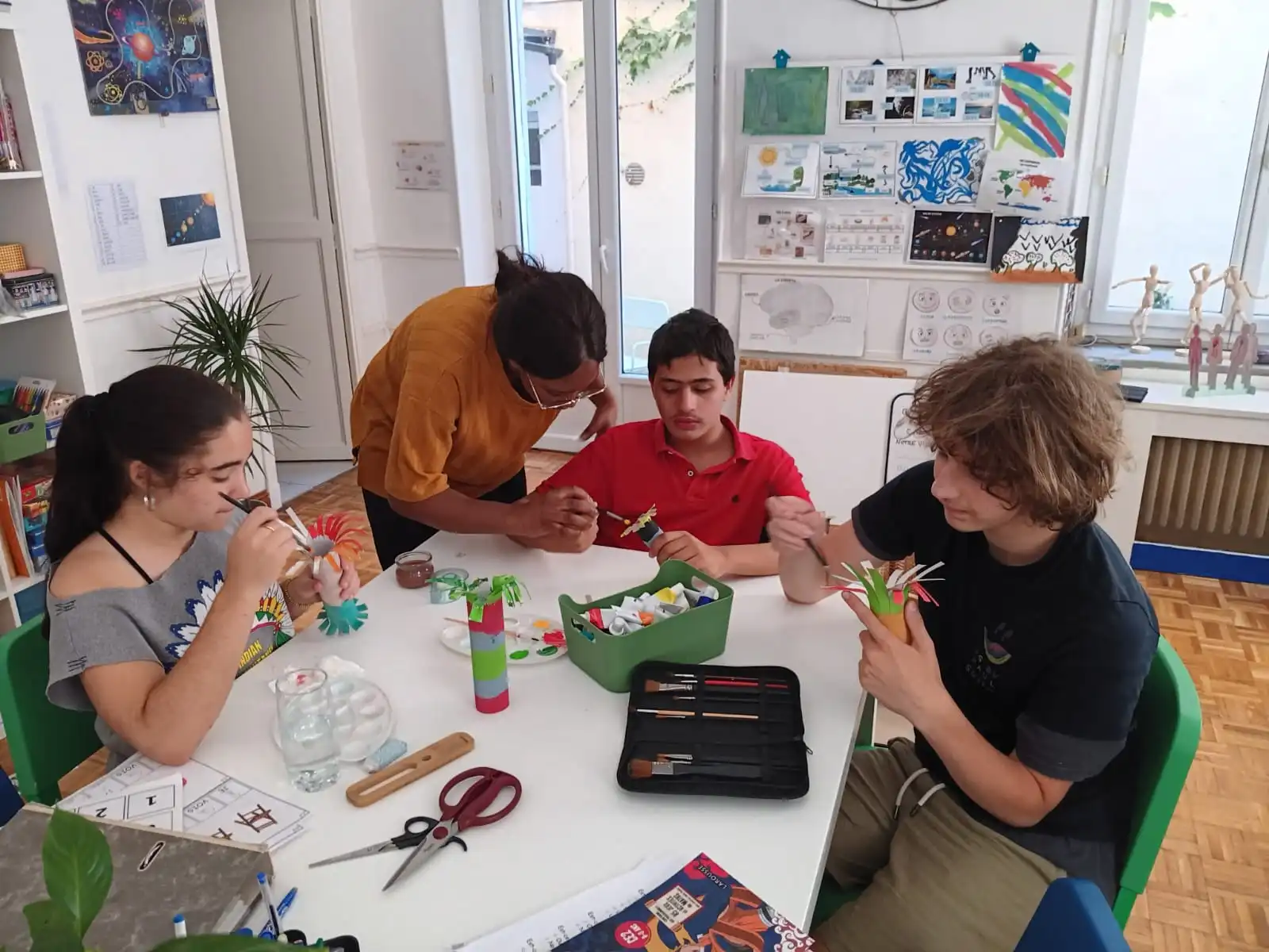 Les enfants faisant une activité autour d'une table, accompagnés de leur éducatrice